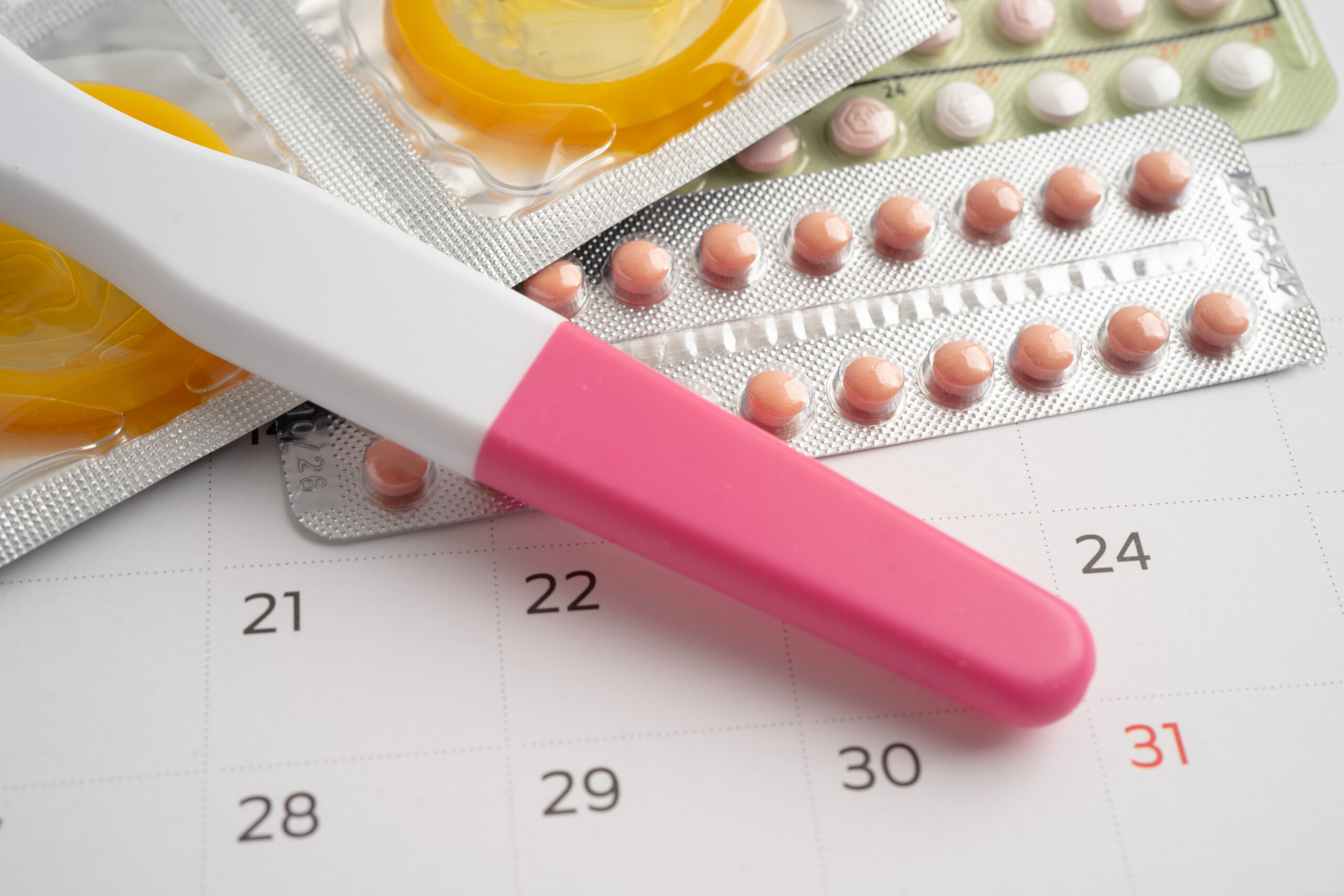 Pregnancy test and birth control pills on calendar, contraceptio